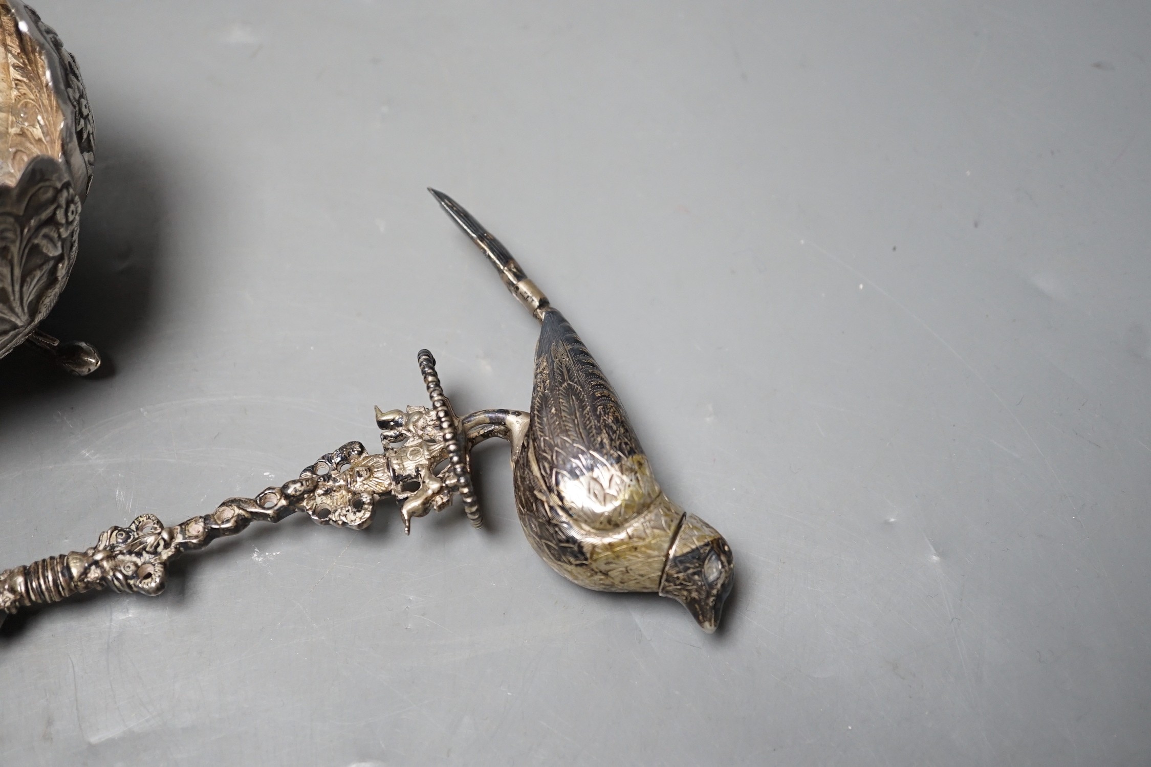 A Dutch white metal toasting fork, with pepperette? finial modelled as a bird, 28.5cm, an Indian white metal double measure cup and a similar bowl.